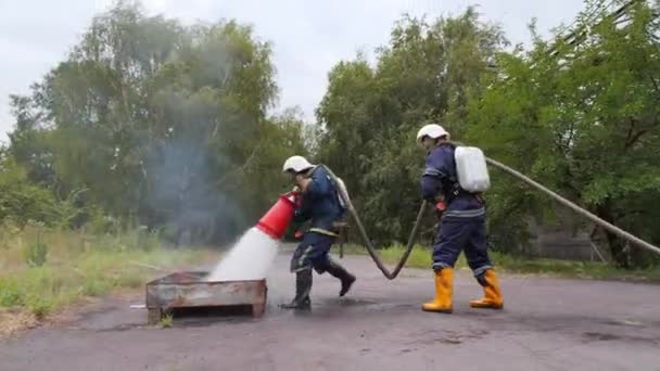 Lehren. Zwei Feuerwehrleute bekämpfen Brand mit Schaum - Filmmaterial, Video