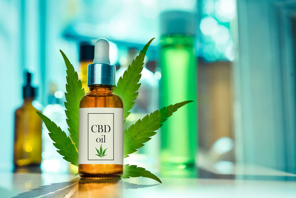 CBD OIL glass bottle, tincture and hemp leaf on a background of a medical laboratory. Concept of legal medicine - Photo, Image