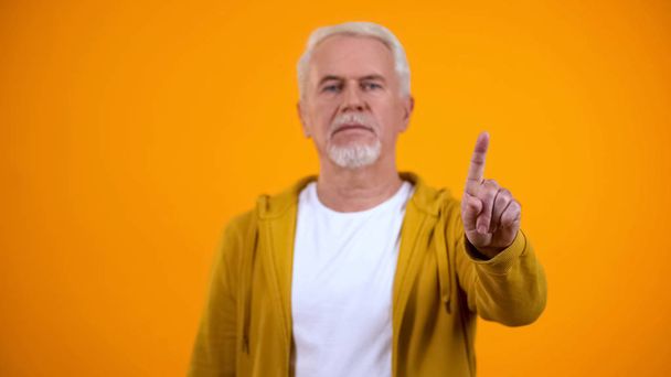 Elderly male in casual clothes showing warning finger gesture, rejection sign - 写真・画像
