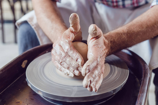 Mann töpfert auf Töpferscheibe macht Keramiktopf aus Ton in Töpferwerkstatt. - Foto, Bild