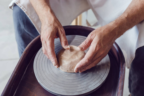 Man potter working on potters wheel making ceramic pot from clay in pottery workshop. - 写真・画像