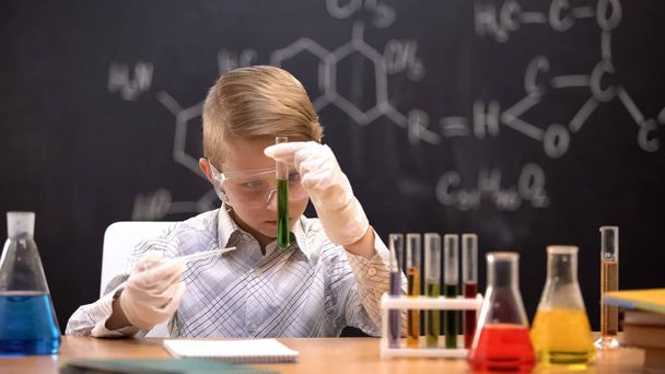 Schoolboy watching reaction in tube with green liquid, chemistry lessons - Φωτογραφία, εικόνα