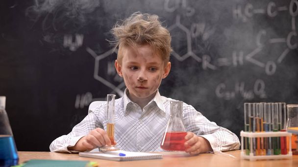 Shocked schoolboy sitting in cloud of smoke, explosion during experiment - Photo, Image