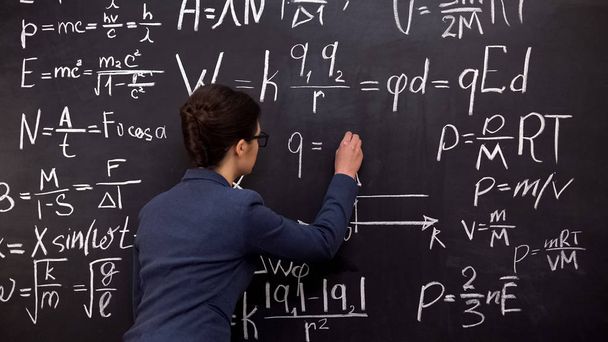 Female tutor writing formula on chalkboard, mathematics lecture, exact sciences - Foto, Bild