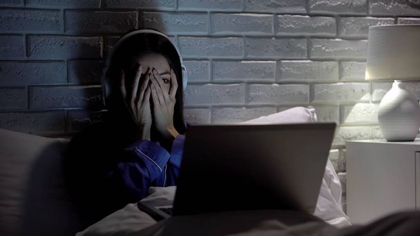 Young female watching scary movie, hiding face in fear, online film service - Fotoğraf, Görsel