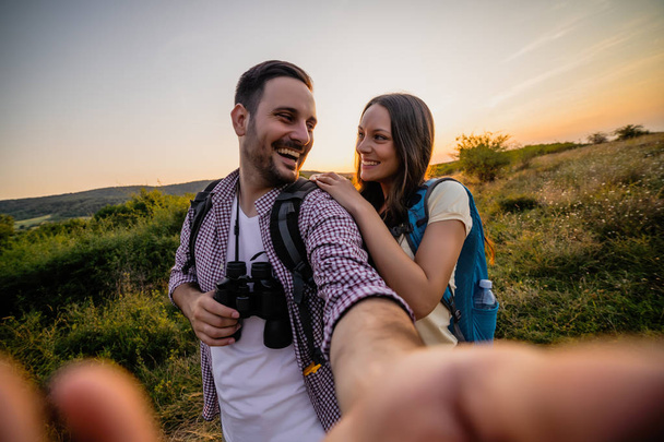Happy couple is hiking. They are having fun with wide ange lens on camera. - Photo, Image