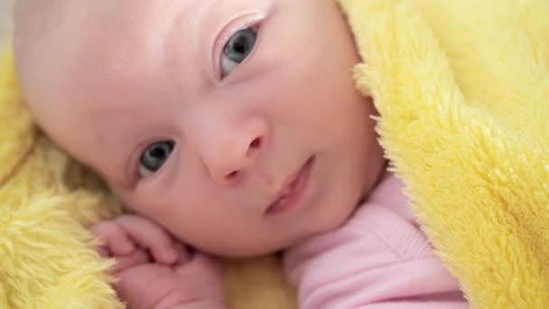Vastasyntynyt vauva makaa hoitopöydällä käärittynä keltaiseen huopaan ja näyttää poispäin.
 - Materiaali, video
