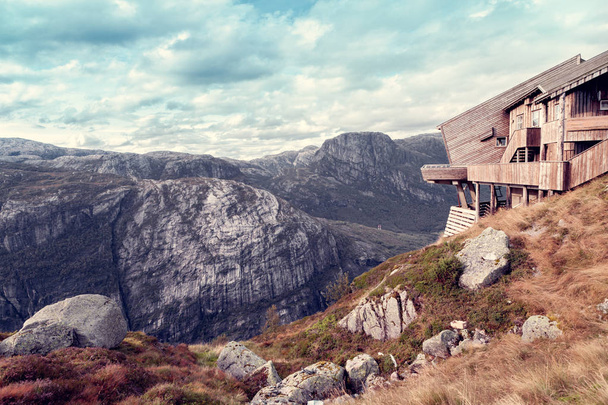 деревянный дом в стиле хай-тек над скалой гор
 - Фото, изображение