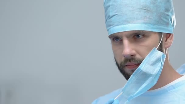 Young medical worker putting on sterile mask, surgery clinic operation, medicine - Felvétel, videó