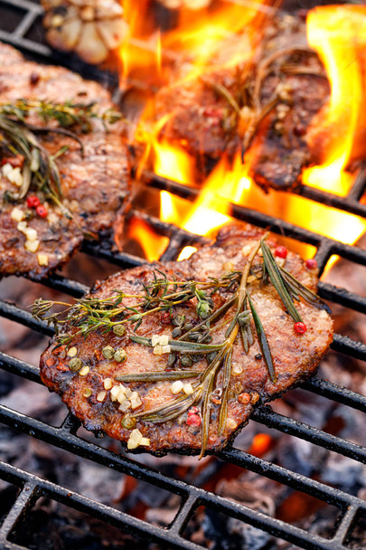 Grillezett sertés nyak, sertés steak azzal a kiegészítéssel, gyógynövények és fűszerek Ona lángoló grillezőlap, közeli, felülnézet. Sült sertéshús, míg grillezés. Grillező, grill hús - Fotó, kép