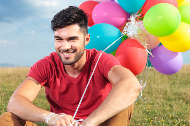 closeup of seated casual man with balloons - Foto, imagen