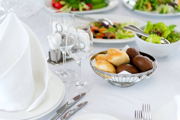 buns of white and black bread on a served table on a background of salads - Foto, Imagem