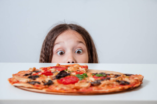 The little girl looks at the pizza. Child found pizza - Photo, image
