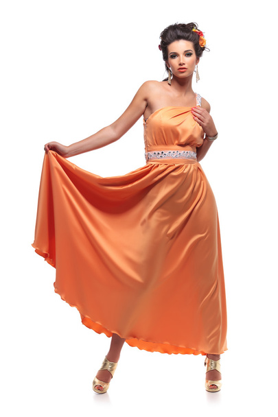 jovem mulher atraente puxando seu vestido longo
 - Foto, Imagem