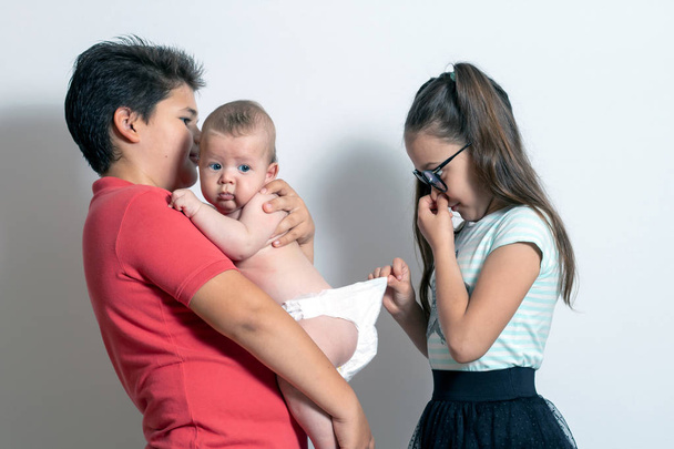 Children change the baby's diaper. Bad smell - Valokuva, kuva