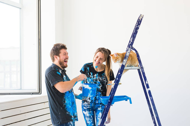 Haustier, Renovierung und Beziehungskonzept - junges lustiges Paar mit Katze renoviert neue Wohnung - Foto, Bild