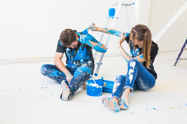Renovation, redecoration and people concept - young couple doing a renovation in new home and have fun at the break - Foto, imagen