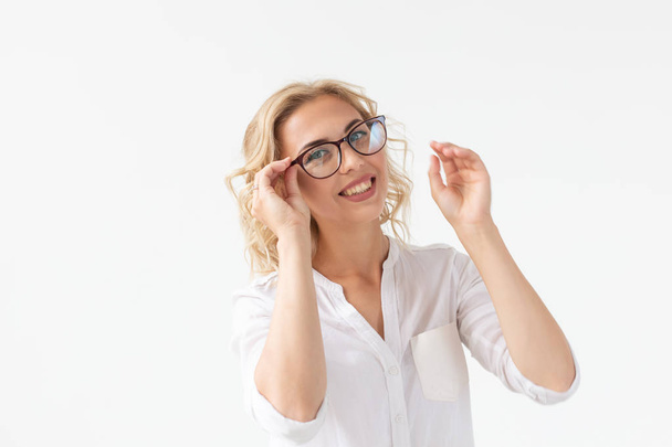 Vision, optics and beauty - Young blond woman putting on a pair of glasses on white background - Фото, зображення