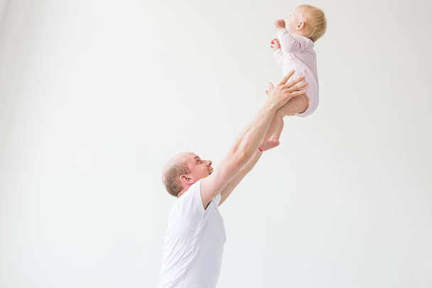 Feliz padre joven levantando lindo bebé en alto en el aire, pasar y disfrutar del tiempo junto con su hija
 - Foto, imagen