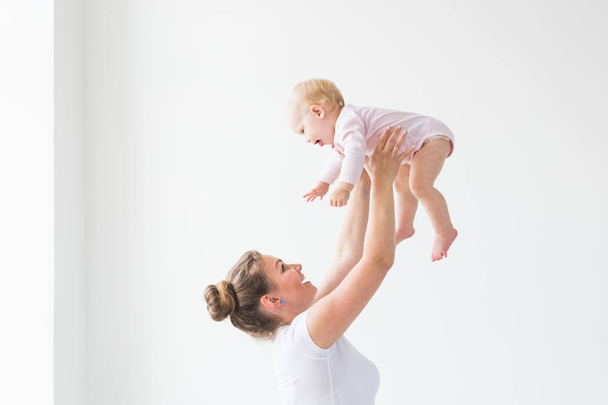 Szczęśliwa młoda matka podnoszenia cute baby się wysoko w powietrzu, wydatków i ciesząc się razem z córką - Zdjęcie, obraz