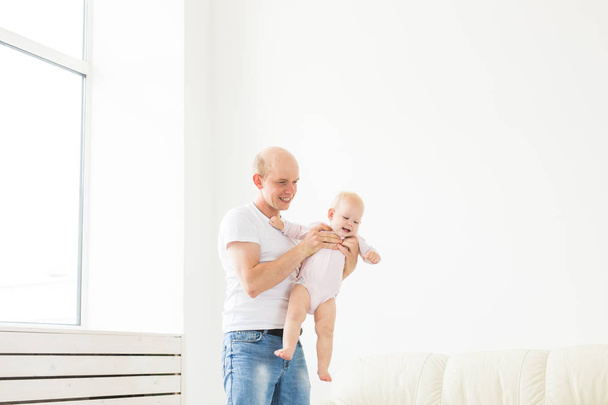 Vaderschap en familieconcept-vader en kleine peuter baby binnenshuis thuis, spelen. - Foto, afbeelding