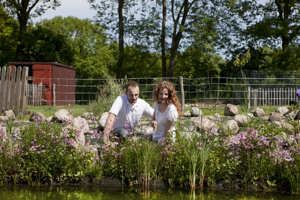 Casal na lagoa de jardim de flores rosa
 - Foto, Imagem