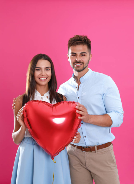 Young couple with air balloon on pink background. Celebration of Saint Valentine's Day - Foto, afbeelding