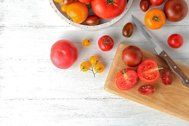 Flat lay composition with fresh ripe whole and cut tomatoes on white wooden table - Фото, изображение