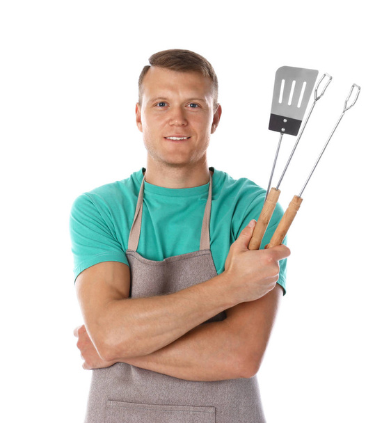 Man in apron with barbecue utensils on white background - Foto, Bild