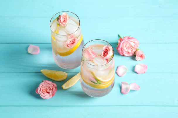 Tasty refreshing lemon drink with roses on light blue wooden table - Фото, зображення