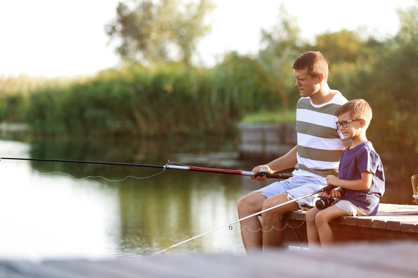 Dad and son fishing together on sunny day - Photo, Image