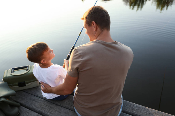 Baba ve oğlu güneşli bir günde birlikte balık tutuyorlar. - Fotoğraf, Görsel