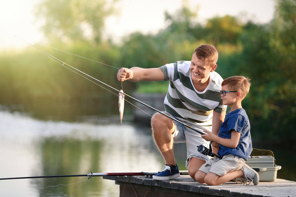 Dad and son fishing together on sunny day - Fotografie, Obrázek