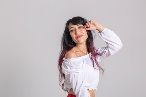 Latina dance, strip dance, contemporary and bachata lady concept - Γυναίκα που χορεύει αυτοσχεδιασμό και κινεί τα μακριά μαλλιά της σε λευκό φόντο - Φωτογραφία, εικόνα
