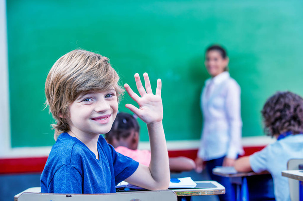 Niño levantando la mano en el aula. - Foto, Imagen
