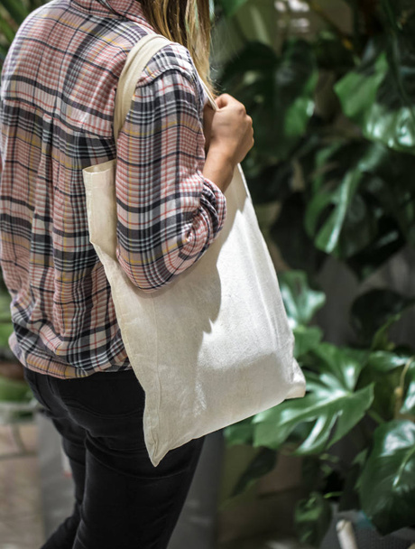 The girl dressed in a plaid shirt holding an eco-bag - Фото, зображення