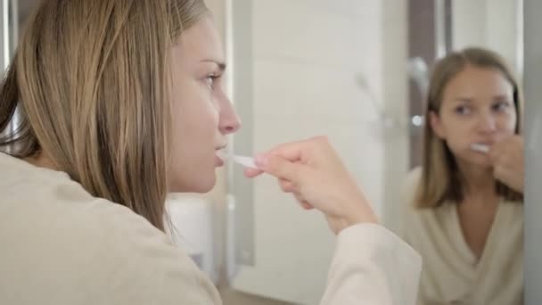 young woman brushes teeth reflecting in mirror - Footage, Video