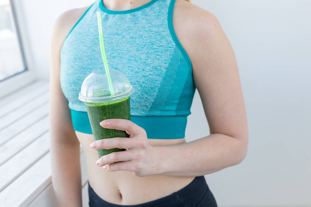 Healthy, sport, diet and people concept - Successful fitness urban woman recommending detox smoothie, close-up - Fotó, kép