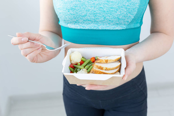 υγιεινή διατροφή, δίαιτα και γυμναστική ιδέα-κοντά στη νεαρή γυναίκα που τρώει λαχανικά και κρέας μετά την προπόνηση - Φωτογραφία, εικόνα