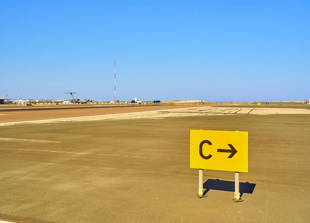 Een landingsbaan van een luchthaven met een militair vliegtuig op de achtergrond - Foto, afbeelding