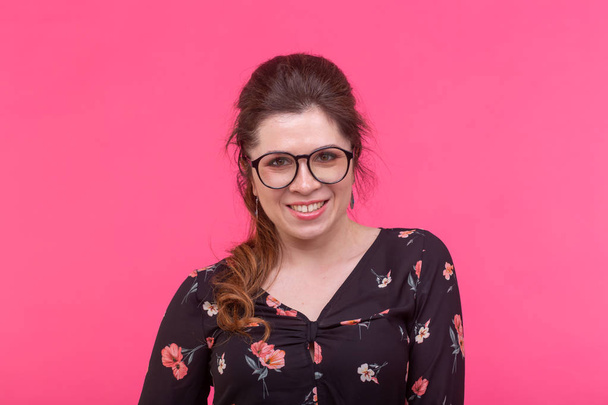 Muotokuva fiksu viehättävä ruskea silmäinen nuori positiivinen nainen silmälasit poseeraa kirkkaan vaaleanpunainen tausta
 - Valokuva, kuva