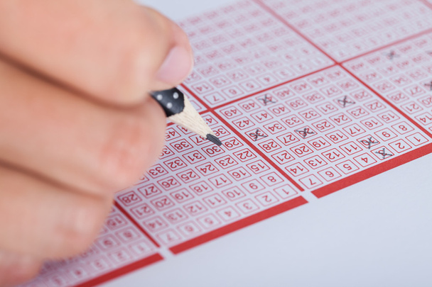 Person Marking Number On Lottery Ticket - 写真・画像