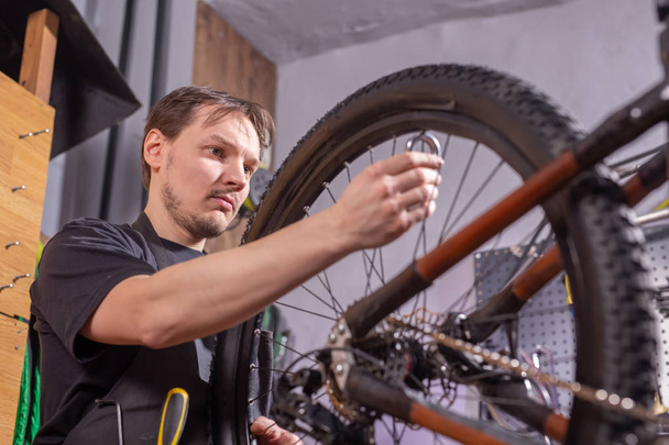 Service, reparatie, fiets en mensen concept-monteur repareren van een mountainbike in een workshop - Foto, afbeelding