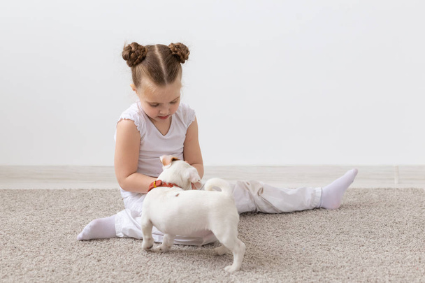 子供の女の子が彼女のジャック ラッセル テリアの子犬を室内で遊ぶ子供、ペットおよび動物の概念- - 写真・画像
