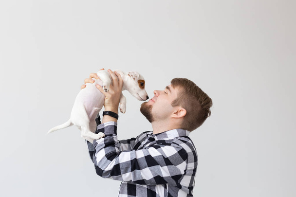 İnsanlar ve evde beslenen hayvan kavramı - portresi yakından jack russell terrier köpek yavrusu oturan adamın elleri - Fotoğraf, Görsel