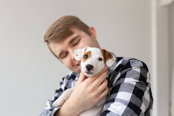 pessoas, animais de estimação e animais conceito - close-up de jovem abraçando Jack Russell terrier filhote de cachorro no fundo branco
 - Foto, Imagem