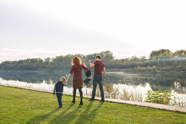 Концепція батьківства, дитинства та природи - Сім'я, що грає з двома синами біля води
 - Фото, зображення
