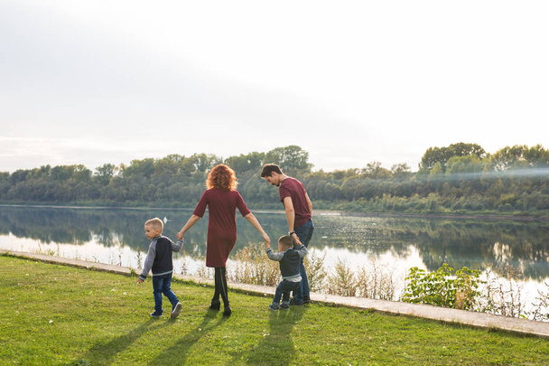 Rodič, dětství a příroda koncept - rodina s dvěma syny u vody - Fotografie, Obrázek