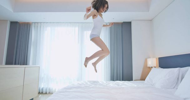 Young woman jump on bed - Fotoğraf, Görsel