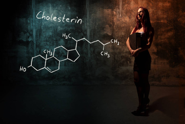 Sexy girl or secretary or female student presenting handdrawn chemical formula of Cholesterol - Photo, Image